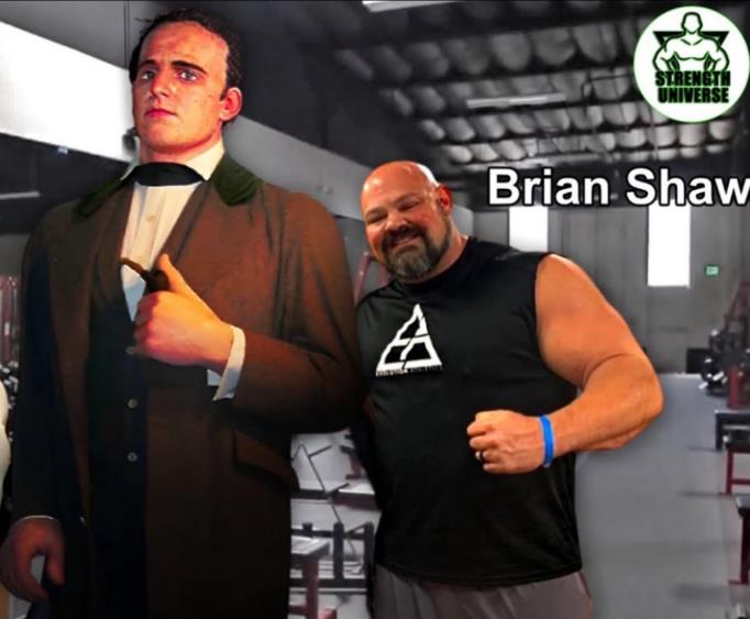 Side-by-side scale comparison in a gym: the Angus MacAskill statue looms beside strongman Brian Shaw, labeled by name, whose shaved head reaches around the statue's shoulder despite Shaw being six-foot-eight and four hundred twenty pounds.